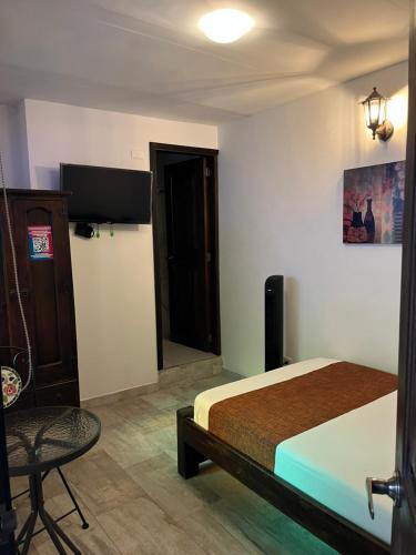 a bedroom with a bed and a tv and a chair at Santiago DC Hotel in Cali
