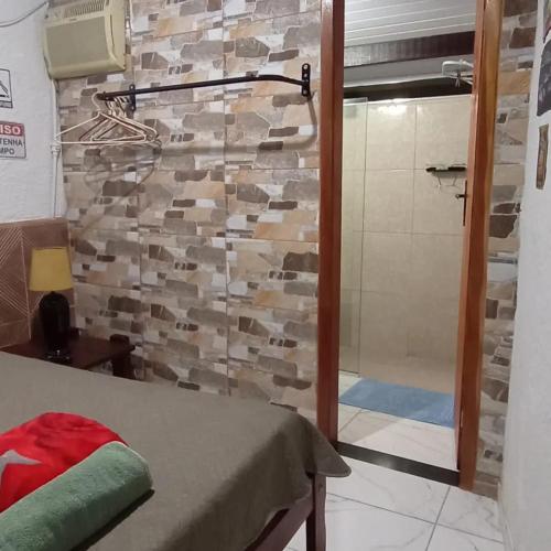 y baño con ducha y pared de piedra. en Quarto Privado-Suite Aconchego-Miguel Pereira / RJ, en Miguel Pereira