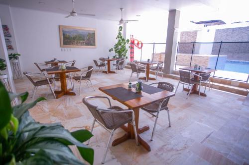 a restaurant with wooden tables and chairs and a large window at Hotel Bella Isa in La Dorada