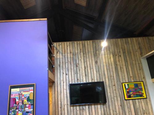 a room with a tv on a wall with paintings at Cabaña Campestre La Rayuela-Fuquene in Fúquene