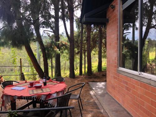 a table with a red table cloth on a patio at Cabaña Campestre La Rayuela-Fuquene in Fúquene