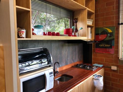 a small kitchen with a sink and a microwave at Cabaña Campestre La Rayuela-Fuquene in Fúquene
