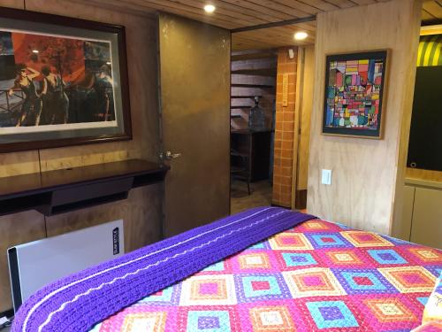 a bedroom with a purple bed and a tv at Cabaña Campestre La Rayuela-Fuquene in Fúquene
