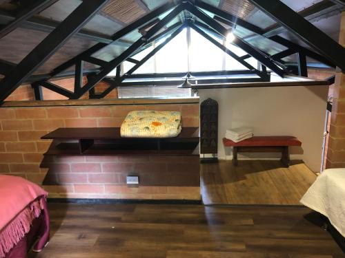 a room with a bed and a bench and a window at Cabaña Campestre La Rayuela-Fuquene in Fúquene