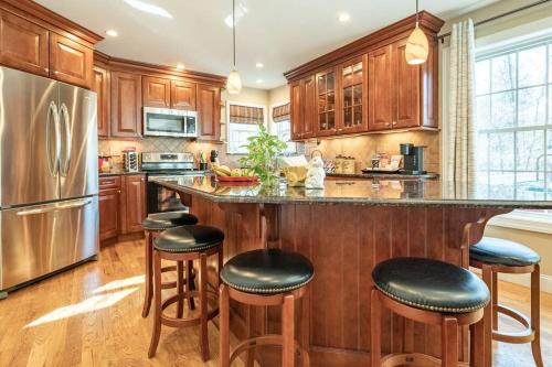 a kitchen with wooden cabinets and a large island with bar stools at Luxury 4 bedroom house in Pocono Mountains with Hottub in Golf Course Near Lake in Tobyhanna