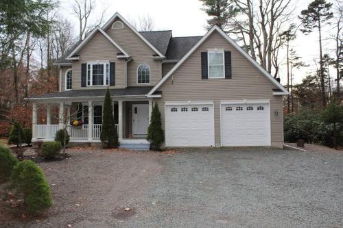 a house with a two garage doors on a driveway at Luxury 4 bedroom house in Pocono Mountains with Hottub in Golf Course Near Lake in Tobyhanna