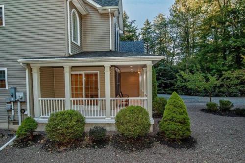 a house with a porch with bushes in front of it at Luxury 4 bedroom house in Pocono Mountains with Hottub in Golf Course Near Lake in Tobyhanna