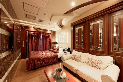 a living room with a bed and a white couch at ホテルパシオンリゾート in Matsuyama