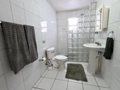 a white bathroom with a toilet and a sink at Traditional Aruban Home close to Surfside Beach in Oranjestad