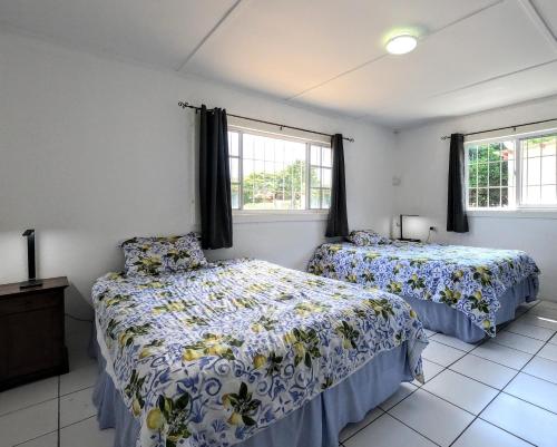 1 Schlafzimmer mit 2 Betten und 2 Fenstern in der Unterkunft Traditional Aruban Home close to Surfside Beach in Oranjestad