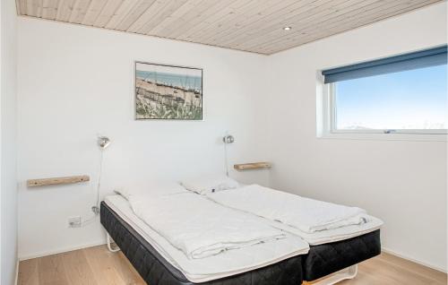 a bed in a white room with a window at Nice Home In Blokhus With 4 Bedrooms, Sauna And Wifi in Blokhus