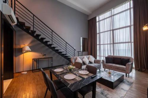 a living room with a table and a staircase at Loft Pano Seaview Suite 2 Bedroom by The Only Bnb in Jelutong