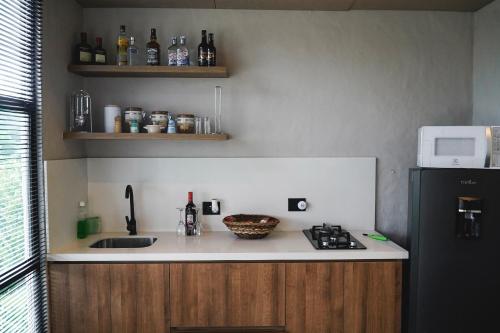 La cuisine est équipée d'un évier, d'une cuisinière et d'un réfrigérateur. dans l'établissement Amanatu Ecolodge & Spa, à Quimbaya