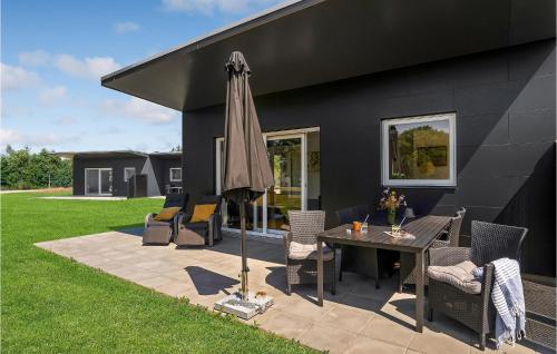 a patio with a table and chairs and an umbrella at Cozy Home In Ringkøbing With Kitchen in Ringkøbing