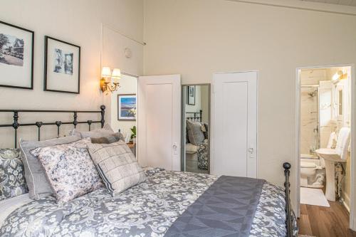 1 dormitorio con cama con almohadas y espejo en 3795 The Artist's Way apts, en Carmel