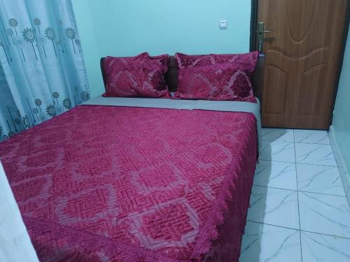 a bed with a red blanket and pillows on it at Cozy & Private 1 Bedroom self contained Kigali-Kanombe in Kigali