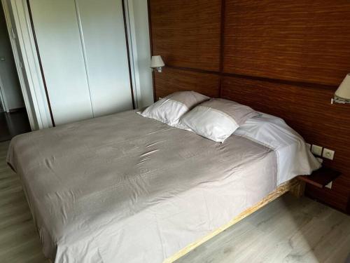 uma cama com lençóis brancos e almofadas num quarto em The place to be em Noumea