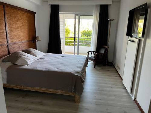 1 dormitorio con cama, TV y balcón en The place to be, en Noumea