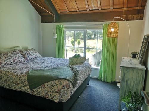 a bedroom with a bed and a window with green curtains at The Gisborne Club - Boutique accommodation in Gisborne