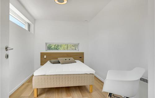 a white bedroom with a bed and a chair at Amazing Home In lbk With 3 Bedrooms And Wifi in Ålbæk