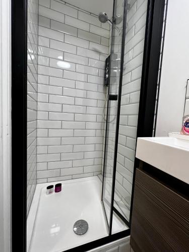 a bathroom with a tub and a shower with a sink at The Farthings, Romsey Apartment in Romsey