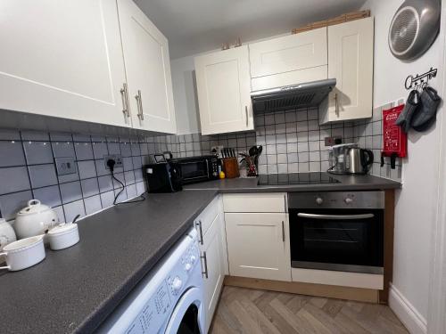 a kitchen with white cabinets and a dishwasher at The Farthings, Romsey Apartment in Romsey