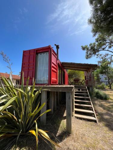 una casa roja en la parte superior de una terraza de madera en El Container de la Playa, en Punta del Diablo