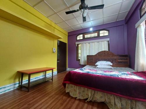 ein Schlafzimmer mit lila und gelben Wänden und einem Bett in der Unterkunft Odyssey Stays Aalo in Along