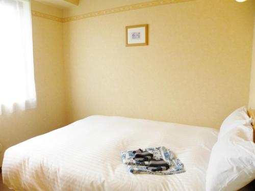 Yonezawa - Hotel / Vacation STAY 16072 في يونيزاوا: سرير أبيض مع كومة من المناشف عليه