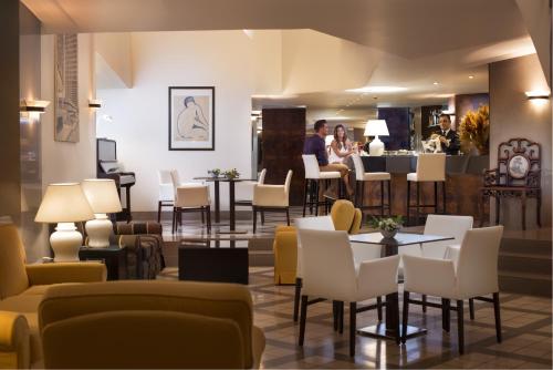 a lobby with tables and chairs and a bar at Sardegna Hotel - Suites & Restaurant in Cagliari