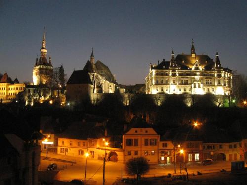 a large building on top of a hill at night at Mercure Sighisoara Binderbubi Hotel & Spa in Sighişoara