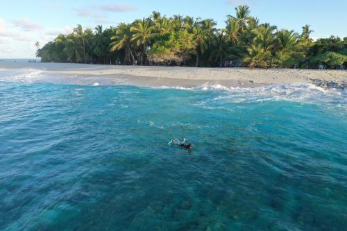 a person swimming in the ocean near a beach at Isle Royal Inn in Fuvahmulah