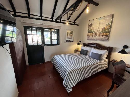a bedroom with a bed with a striped comforter at Casa Villa Pepita in Villa de Leyva