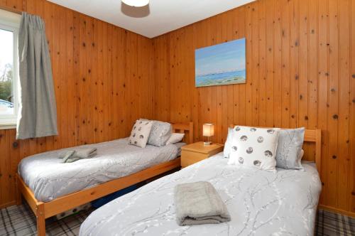 two beds in a room with wood paneled walls at Holy Loch Lodge in Hunters Quay
