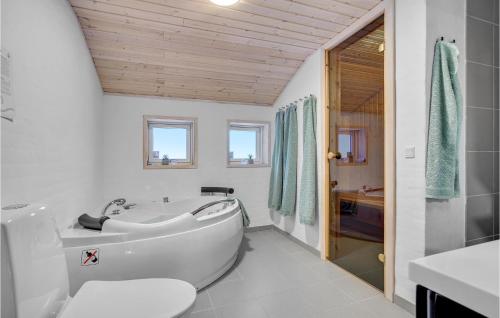 a bathroom with a tub and a toilet and a sink at Cozy Home In lbk With Kitchen in Ålbæk