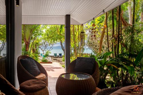 a porch with two chairs and a table and trees at Sunshine Residence in Baan Tai