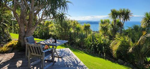 a table and a chair sitting on a patio with the ocean at Nikau Apartments Waiheke Island in Onetangi