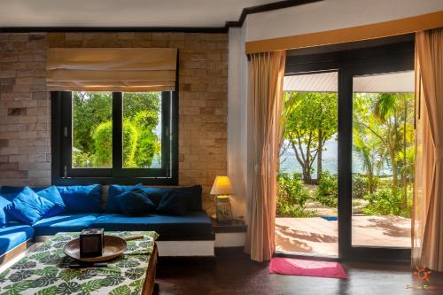 a living room with a blue couch and a window at Sunshine Residence in Baan Tai