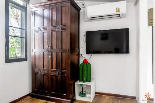a room with a large wooden door and a tv at Sunshine Residence in Baan Tai