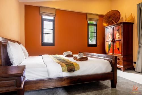 a bedroom with a bed with orange walls and windows at Sunshine Residence in Baan Tai