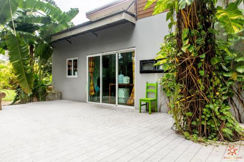 a patio of a house with a green chair at Sunshine Residence in Baan Tai