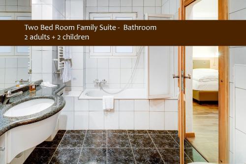 a bathroom with a sink, toilet and mirror at Alpen Resort Hotel in Zermatt