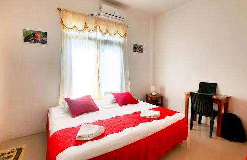 a bedroom with a large bed with red sheets and a window at Cielo Azul Galápagos Hotel in Puerto Villamil