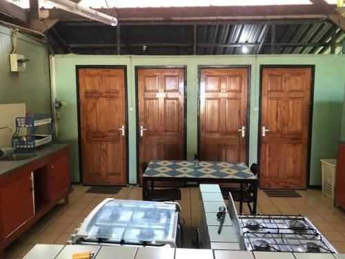 a kitchen with wooden doors and a table in it at Unu Pikin Guesthouse in Paramaribo