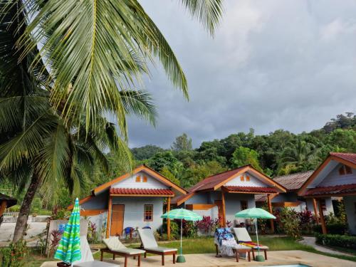 a resort with chairs and umbrellas and a palm tree at Khaolak Banana Bungalow in Khao Lak