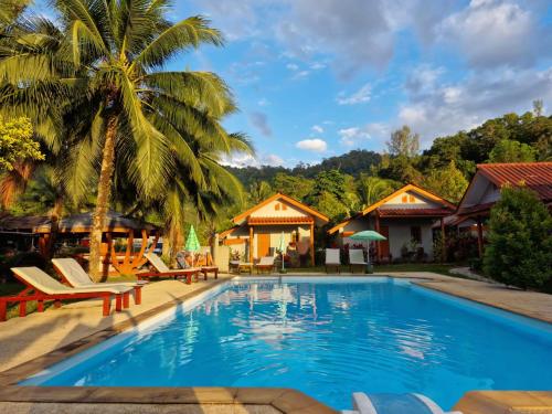a pool at a resort with a palm tree at Khaolak Banana Bungalow in Khao Lak