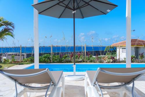 a patio with an umbrella and chairs next to a pool at Crystal Villa ikema in Miyako Island