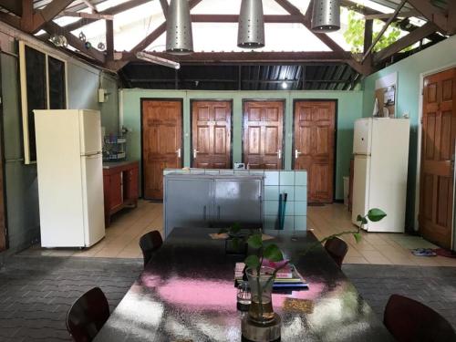 a kitchen with a table and two white refrigerators at Unu Pikin Guesthouse in Paramaribo