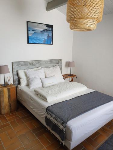 um quarto com uma cama grande com lençóis brancos e almofadas em La Villa du Tesselier em Noirmoutier-en-l'lle