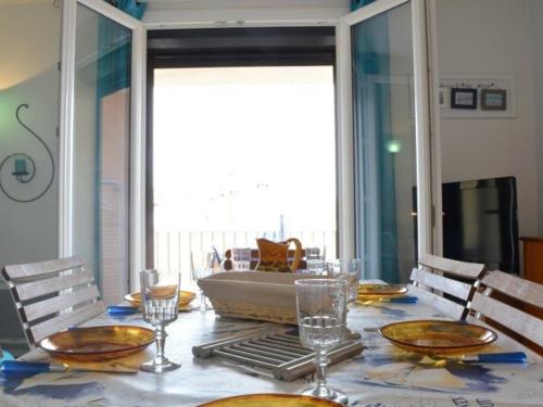 une table de salle à manger avec des chaises et une grande fenêtre dans l'établissement Appartement 3 pièces avec balcon, 150m de la plage, 6 couchages, Narbonne Plage - FR-1-229B-701, à Narbonne